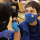 A healthcare worker prepares to give a vaccine to a patient. Both people are wearing medical face masks. 